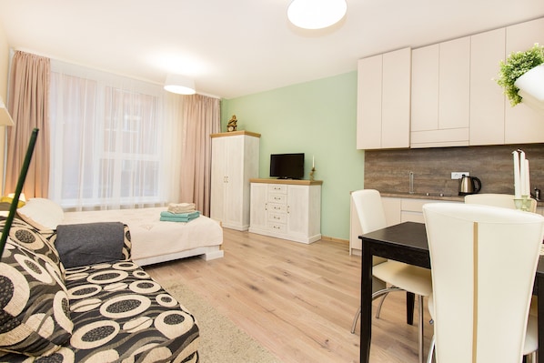 Ein modernes Wohnzimmer mit einer Couch, einem Esstisch mit Stühlen, einem Fernseher und einem Schrank.