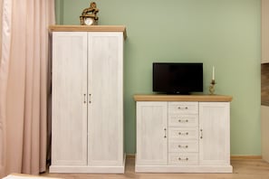 Ein Zimmer mit großem Kleiderschrank, Fernseher auf einem Schrank und einem Vorhang.