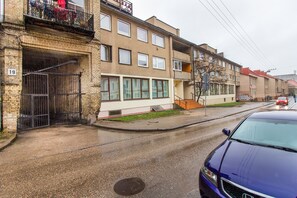 Un edificio residencial de varios pisos con fachada de ladrillo, ventanas grandes y una entrada visible con una reja de metal.