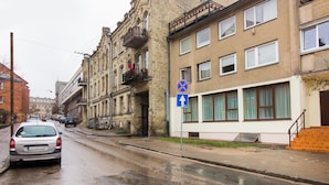 A street with buildings, a no parking sign, and a car.