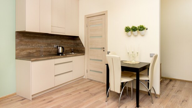 A modern kitchen with light-colored cabinets, a wooden countertop, and a dining area with a table and chairs.