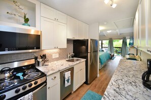 A modern kitchen with white cabinets, a stainless steel refrigerator, and a black stove.