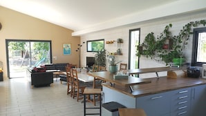 Et moderne køkken med en central ø, spiseplads med stole, og en stue med en sofa.