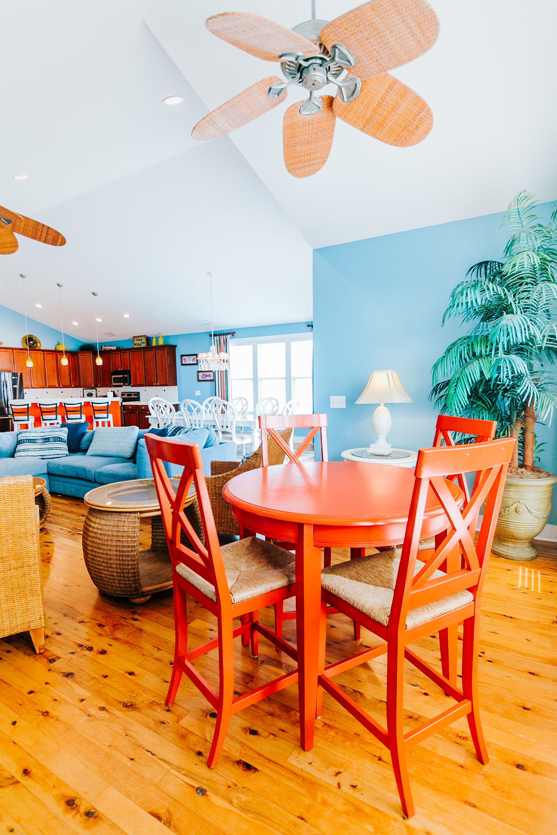 Un salon moderne avec un mur bleu, un plancher en bois, une table ronde orange et des chaises rouges.