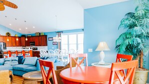 A modern living room with a blue wall, wooden flooring, a round orange table, and red chairs. -  6 bedroom-5.5 bathrooms in the heart of Garden City Beach and Heated Pool (Murrells Inlet)