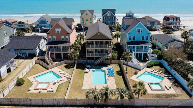 A beachfront property with multiple houses, a swimming pool, and a beach view. -  6 bedroom-5.5 bathrooms in the heart of Garden City Beach and Heated Pool (Murrells Inlet)
