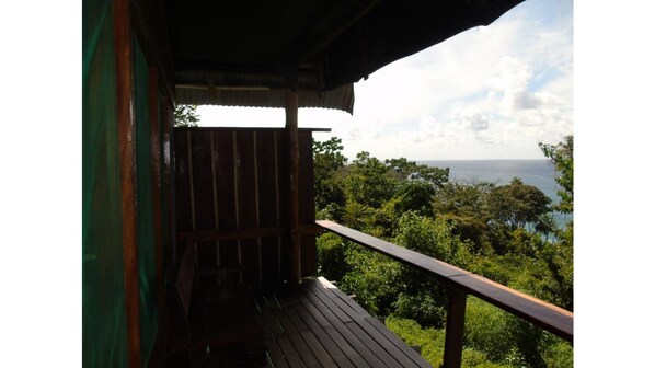 Enjoy breathtaking views of the lush landscape and serene body of water from this balcony.