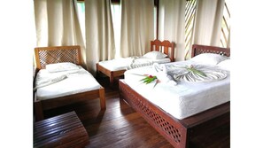 Cozy retreat with a large bed, two smaller beds, and a wooden bench.