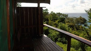 Eine Holzterrasse mit Blick auf eine üppige Landschaft und das Meer.