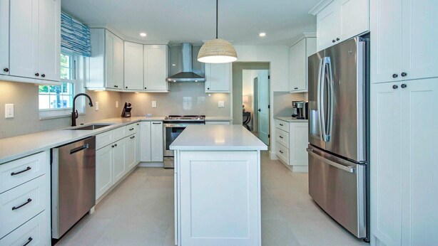 Una cocina moderna con armarios blancos, electrodomésticos de acero inoxidable y una isla central.