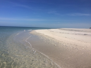 Una playa con aguas poco profundas y cristalinas y una orilla arenosa.
