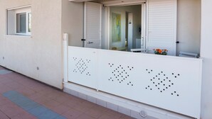 A white balcony with a window and a door, a tiled floor, and a small window to the left.