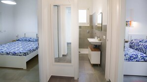 A modern bedroom with two beds, a bathroom, and a shower.