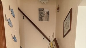 Eine Treppe mit Marmorstufen, einem Holzgeländer und einer Fußmatte am Fuß.