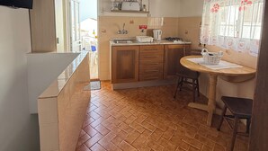 Eine Küche mit Holzbalken, gefliestem Boden und einem Essbereich mit Tisch und Stühlen.