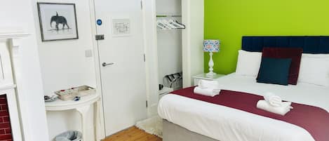 A hotel room with a bed, a nightstand, a lamp, a wardrobe, and a trash bin.
