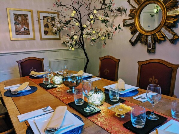 A dining table set with plates, glasses, and a decorative centerpiece. - Guestling Hall Hotel (Hastings)