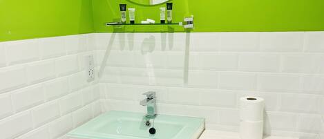 A bathroom with a white sink, toilet, and green walls.