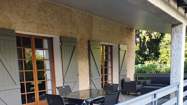 An outdoor patio area with a table and chairs, a stone wall, and a wooden fence. - Palavesa City (Porto-Vecchio)
