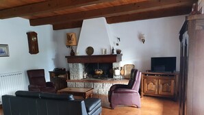 A cozy living room with a stone fireplace, leather sofas, and a television. - Palavesa City (Porto-Vecchio)