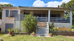 A two-story house with a covered porch, a stone staircase, and a fenced yard. - Palavesa City (Porto-Vecchio)