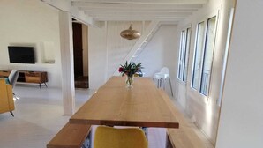 A spacious dining area with a long wooden table, yellow chairs, and a vase of flowers.