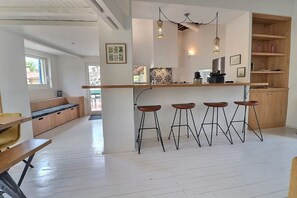 Une cuisine moderne avec un coin bar, des tabourets en bois et des luminaires suspendus.