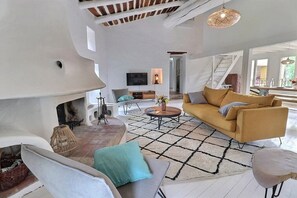 Un salon moderne avec une cheminée, un canapé, une table basse et un téléviseur.