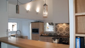A modern kitchen with wooden countertops, a built-in oven, and pendant lighting.