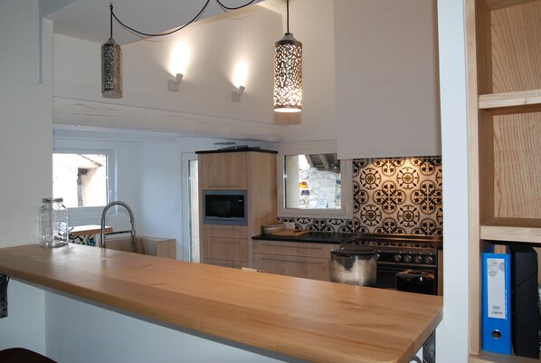 Una cocina moderna con encimeras de madera, horno integrado e iluminación colgante.