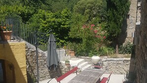 A patio area with outdoor furniture, a barbecue grill, and potted plants.