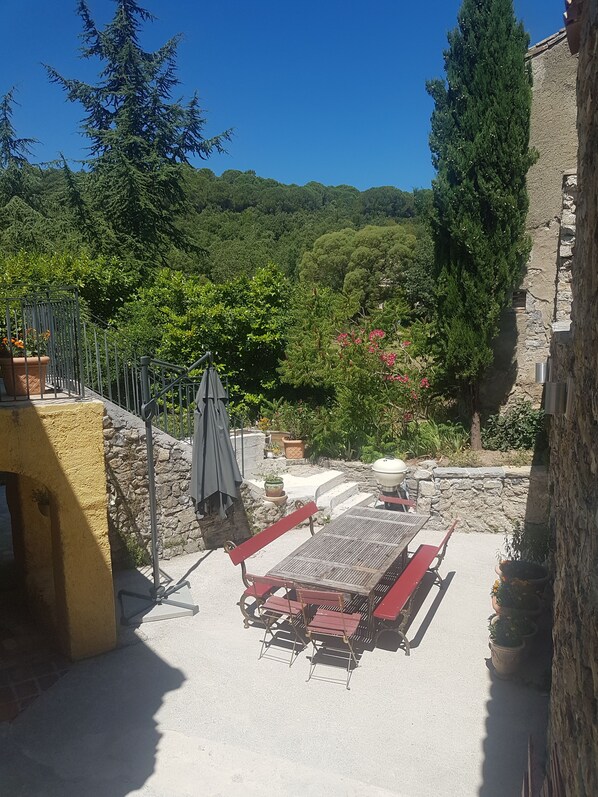 Un espacio de patio con mobiliario exterior, una parrilla y plantas en macetas.