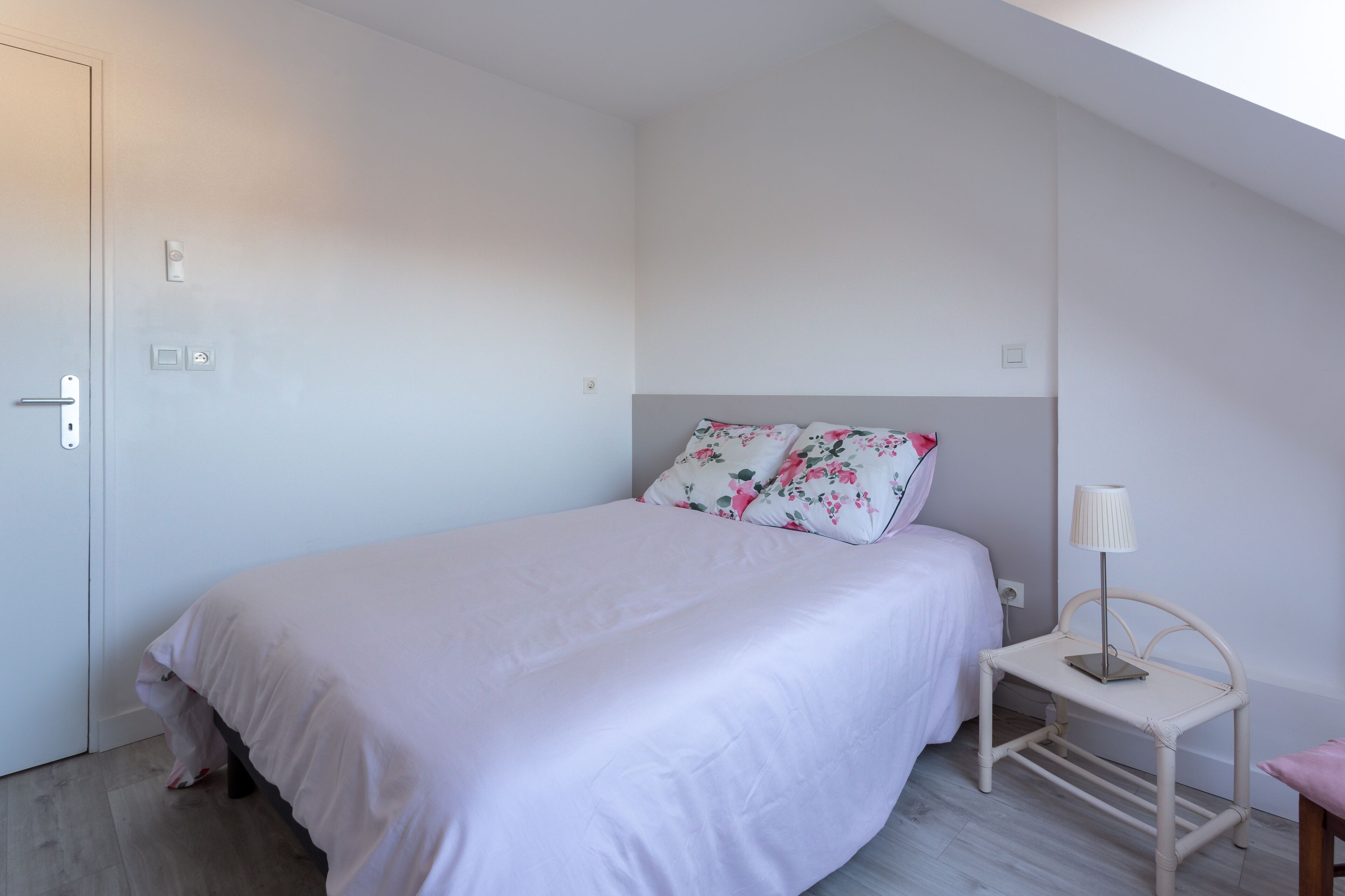 Un dormitorio con cama, mesita de noche, lámpara y una puerta.