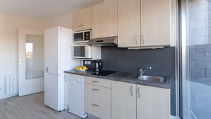 Eine moderne Küche mit hellen Holzschränken, Edelstahlgeräten und einer schwarzen Arbeitsplatte.