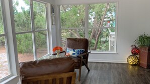 A spacious room with large windows, a wooden floor, and two leather chairs.