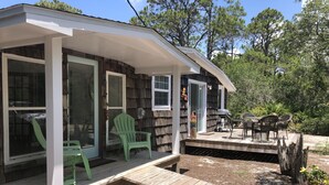 A wooden deck with a covered porch, a table and chairs, and a small garden area.