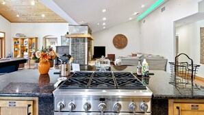 Une cuisine moderne équipée d’une cuisinière à gaz, un coin repas avec un billard et un salon agrémenté d’une cheminée.