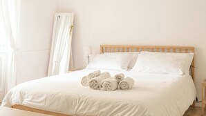 A neatly made bed with white linens and rolled towels, a wooden headboard, and a bedside table with a lamp. - The Angolino apartment (TN)