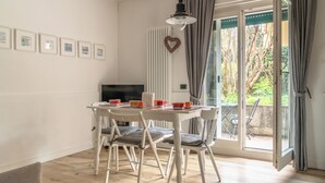 A dining area with a table set for four, white chairs, a television on the wall, and a heart-shaped decoration. - The Angolino apartment (TN)