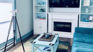 Un salon équipé d’un téléviseur, d’une cheminée, d’étagères et d’un trépied.