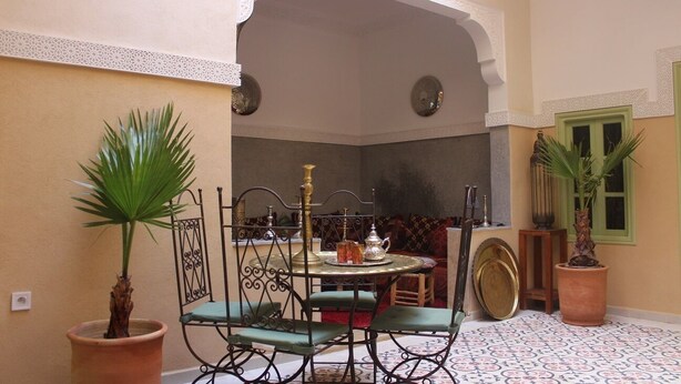 A dining area with a round table, chairs, and a decorative archway. - Riad la medersa in Marrakesch (Marrakech)