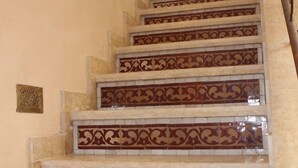 A staircase with ornate red and white tile patterns and a blue decorative object at the top. - Riad la medersa in Marrakesch (Marrakech)
