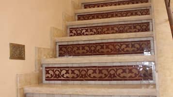 Una escalera con intrincados diseños de baldosas rojas y blancas, y un objeto decorativo azul en la parte superior.