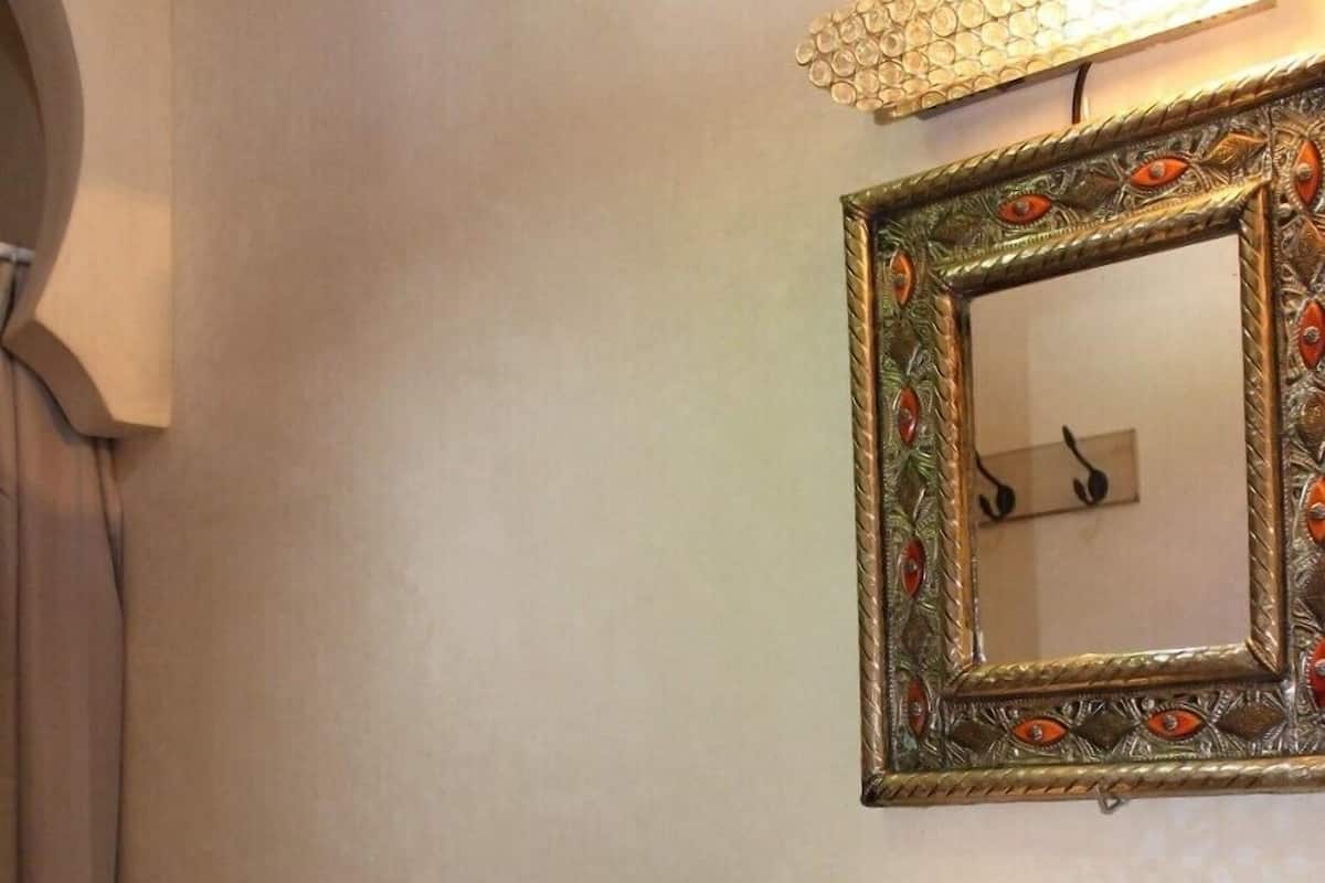 A bathroom with a granite countertop, a gold sink, a white toilet, and a decorative mirror with a floral frame.