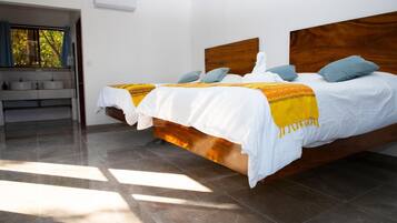 Una habitación de hotel con dos camas, un baño con lavamanos y una ventana con cortinas.