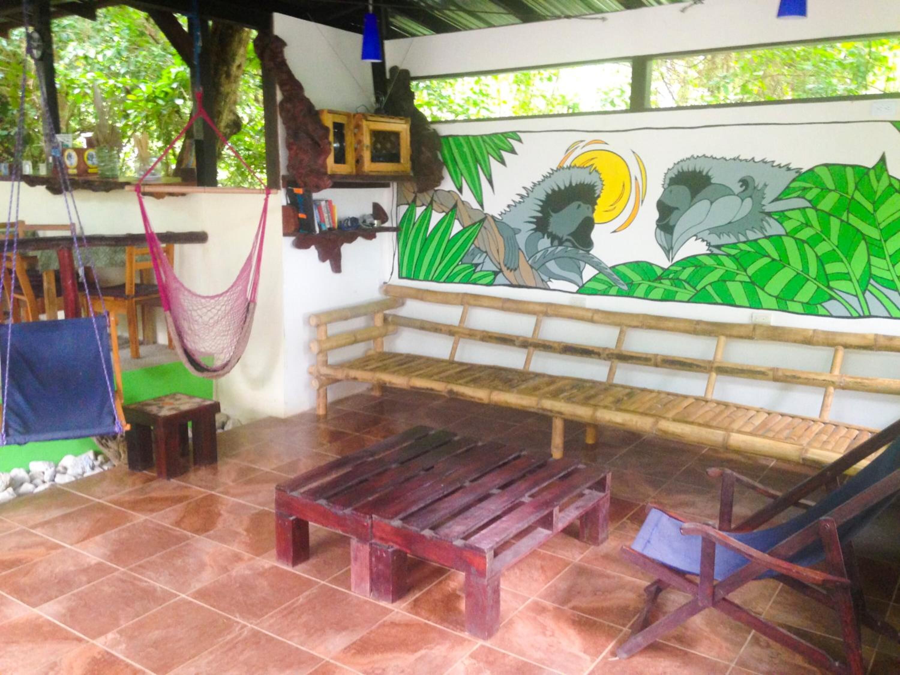 Quarto com um banco de madeira, uma rede e um mural de um pássaro e folhagem.