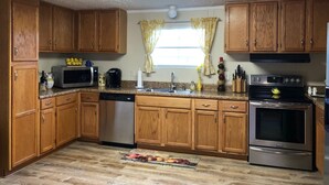 A kitchen with wooden cabinets, a microwave, a dishwasher, a sink, and an oven. - Charming 3BR 2BA Lakefront Lake Norman Home with Beach & Dock - Sleeps 10 (Sherrills Ford)