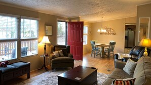 A living room with a sofa, a coffee table, a dining table with chairs, and a kitchen area in the background. - Charming 3BR 2BA Lakefront Lake Norman Home with Beach & Dock - Sleeps 10 (Sherrills Ford)