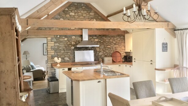 Una cucina rustica con parete in pietra, travi in legno e isola centrale.