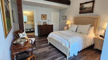 A bedroom with a bed, a wooden ceiling fan, a chair, a dresser, and a mirror.